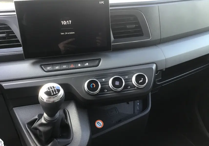 Vue intérieure du tableau de bord du Renault Master gris urbain 2025, avec écran tactile et levier de vitesse manuel.