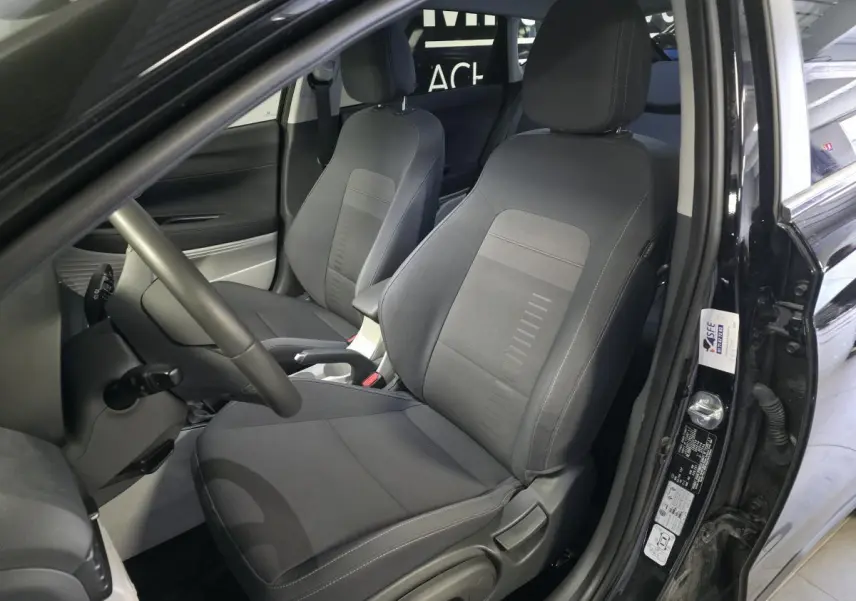 Intérieur avant du Hyundai Bayon noir, vue côté conducteur montrant sièges tissu gris et accoudoir central.