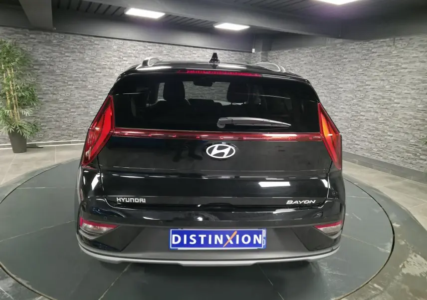 Vue arrière d'une Hyundai Bayon noire avec feux arrière LED et logo Hyundai bien visibles en intérieur showroom.