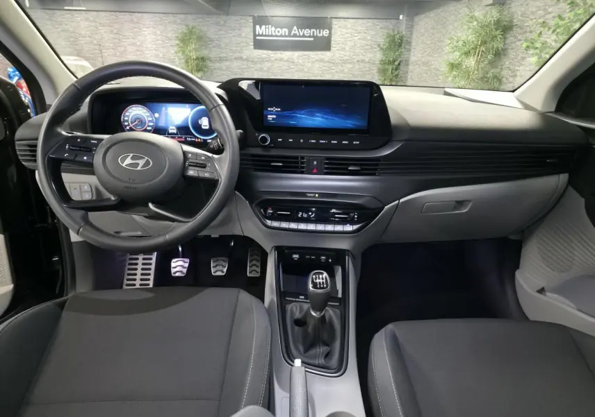 Intérieur bi-ton noir et gris clair de la Hyundai BAYON 2025, vue frontale sur tableau de bord et levier manuel.