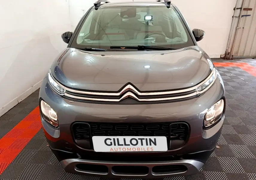 Vue avant d'un Citroën C3 Aircross gris métallisé avec calandre chromée et phares LED allumés en intérieur.