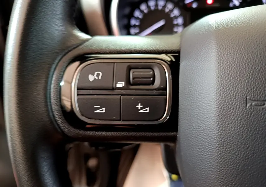 Gros plan sur les commandes multifonctions noires du volant cuir d'une Citroën C3 Aircross 2020.