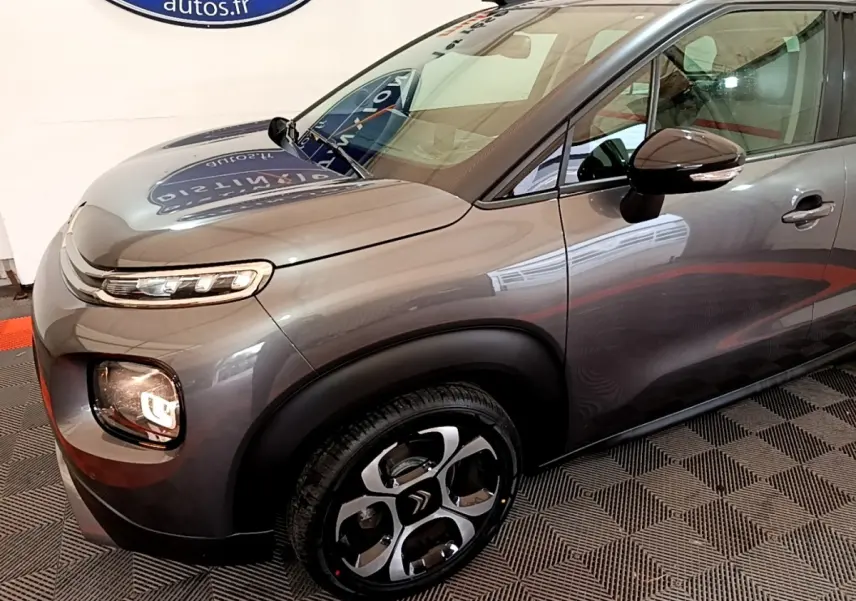 Vue 3/4 avant droit d'un Citroën C3 Aircross gris métallisé avec jantes distinctives et rétroviseurs ton caisse.