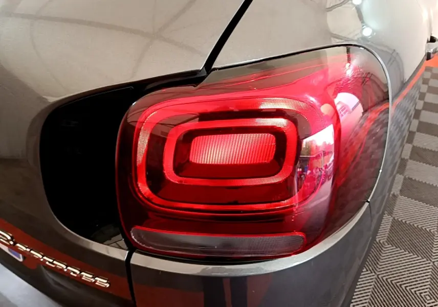 Gros plan sur le feu arrière droit rouge d'un Citroën C3 Aircross gris 2020, avec logo partiel visible sur le coffre.