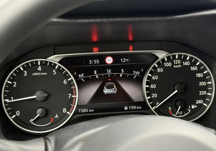 Tableau de bord du Nissan Juke 2025 essence, affichage numérique central et compte-tours à gauche.