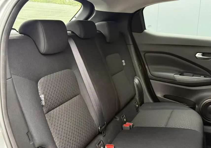 Vue latérale droite de la banquette arrière noire du Nissan Juke 2025 avec ceintures et appuie-têtes intégrés.