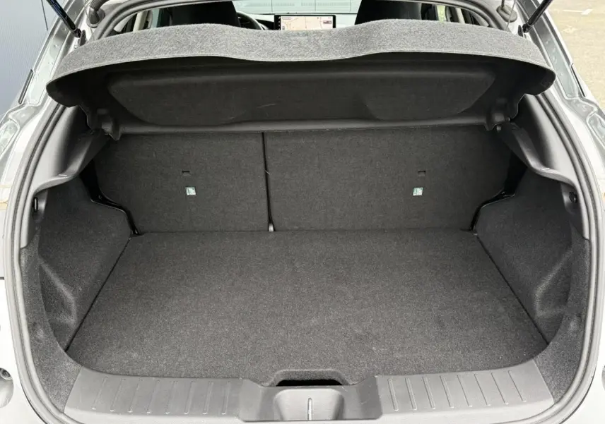 Vue arrière ouverte du coffre spacieux et propre d'un Nissan Juke 2025 gris foncé, sans chargement visible.