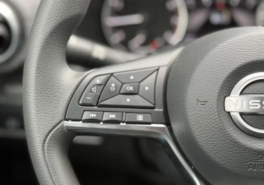 Gros plan sur le volant noir du Nissan Juke 2025, mettant en valeur les commandes multifonctions à gauche.