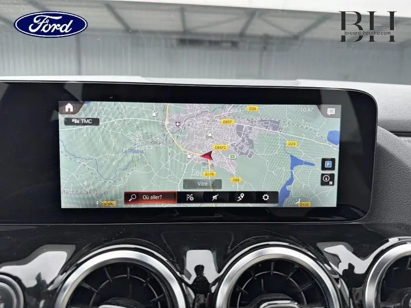 Vue intérieure centrée sur l'écran tactile GPS du tableau de bord d'une Mercedes Classe B noire cosmos métallisé.