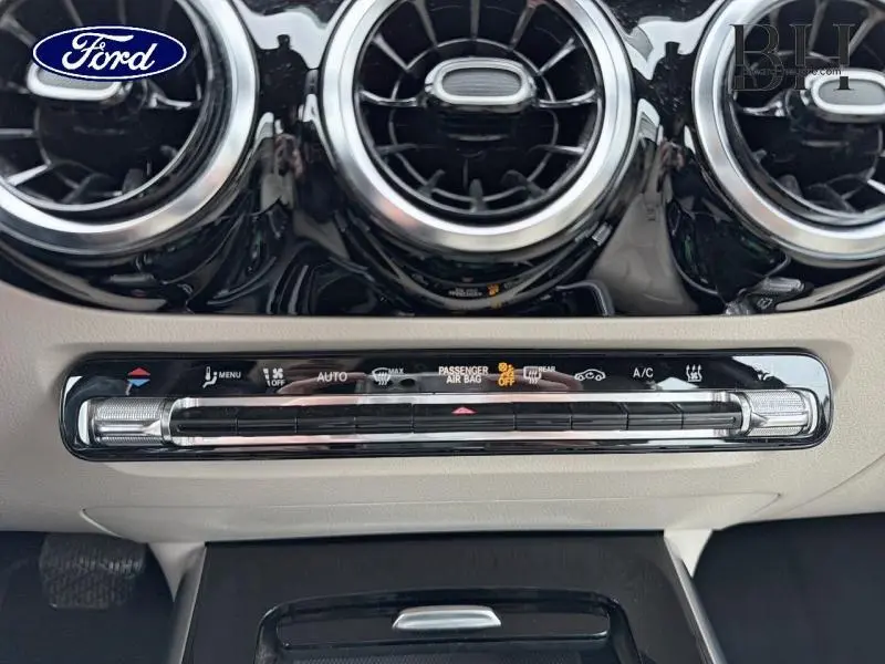 Gros plan sur la console centrale beige avec commandes climatisation et aérateurs ronds noirs brillants Mercedes Classe B 2021