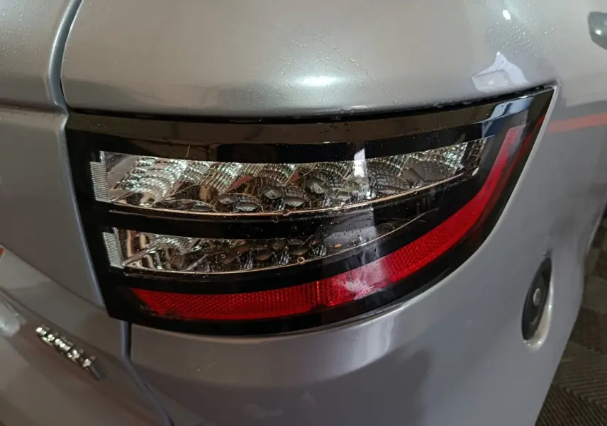 Gros plan sur le feu arrière droit gris clair de l'AIXAM AMBITION 0.5 CITY PACK 2026 avec détails lumineux et carrosserie lisse.