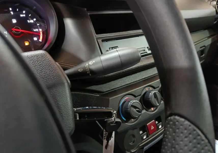 Vue intérieure rapprochée du tableau de bord et volant de l'AIXAM AMBITION 0.5 CITY PACK gris clair, avec commandes de climatisation visibles.