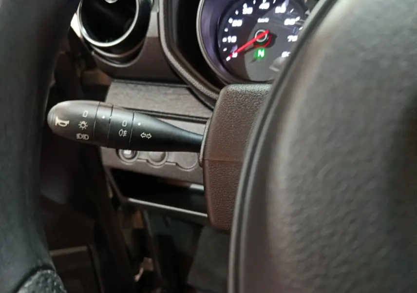 Gros plan sur le commodo d’éclairage à gauche du volant dans l’habitacle de l’AIXAM Ambition gris clair 2026.