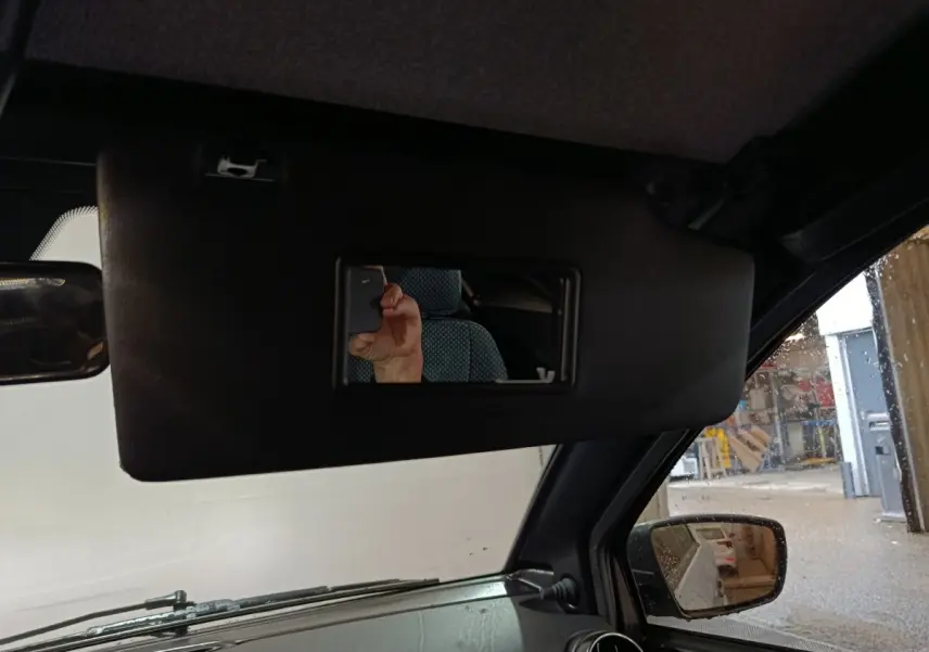 Vue intérieure côté conducteur de l'AIXAM Ambition gris clair 2026, avec pare-soleil et rétroviseur extérieur caméra visible.