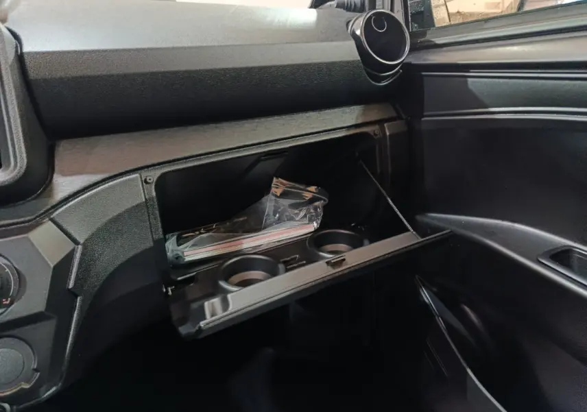 Intérieur de l'AIXAM AMBITION 0.5 CITY PACK 2026, vue sur la boîte à gants ouverte avec porte-gobelets intégrés.