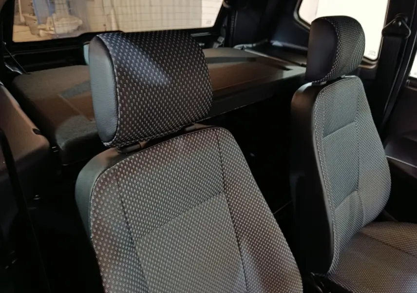 Gros plan sur les sièges avant en tissu gris d’une Aixam Ambition 0.5 City Pack 2026, intérieur sobre et fonctionnel.