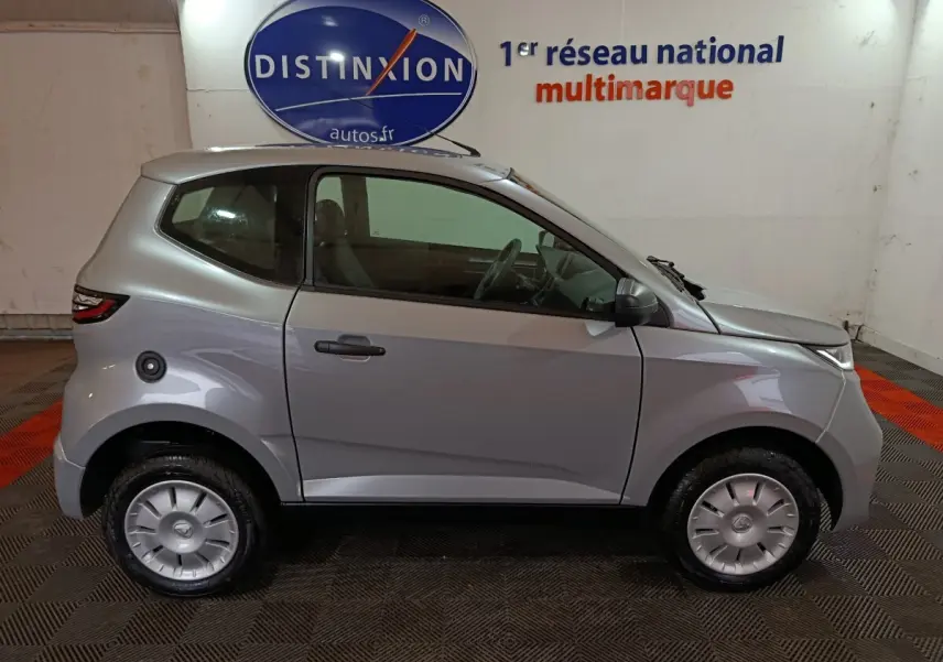 Vue de profil côté gauche d'une Aixam Ambition 0.5 City Pack gris clair 2026 avec rétroviseur caméra côté conducteur.