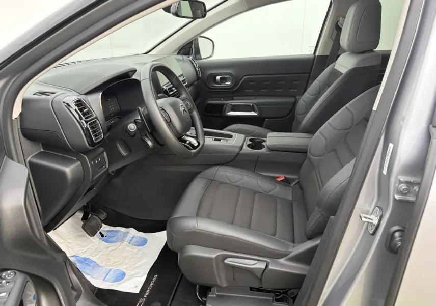 Vue intérieure côté conducteur du Citroën C5 Aircross gris métal 2024, sièges noirs et tableau de bord moderne.