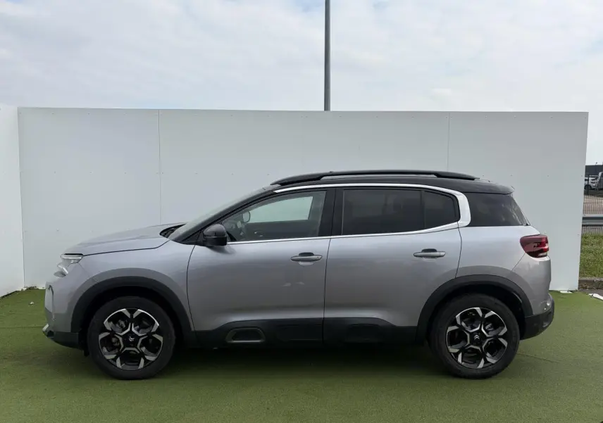 Profil droit d'un Citroën C5 Aircross gris métal 2024 avec toit noir bi-ton et jantes alliage 18 pouces.