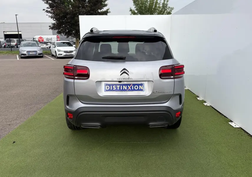 Vue arrière d'un Citroën C5 Aircross gris métal avec toit noir et feux arrière LED 3D, stationné sur sol vert.