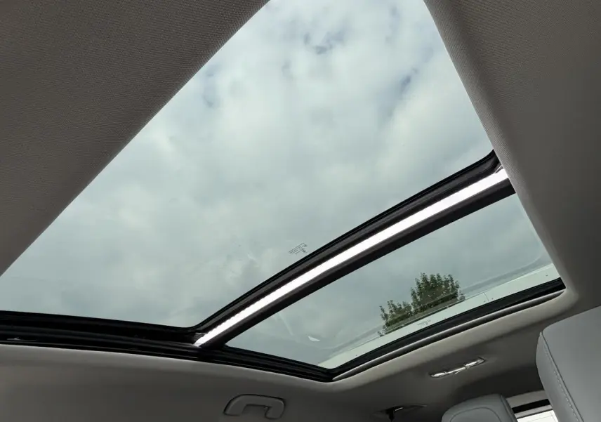 Vue intérieure du toit ouvrant panoramique vitré du Citroën C5 Aircross gris métal, avec ciel nuageux visible.