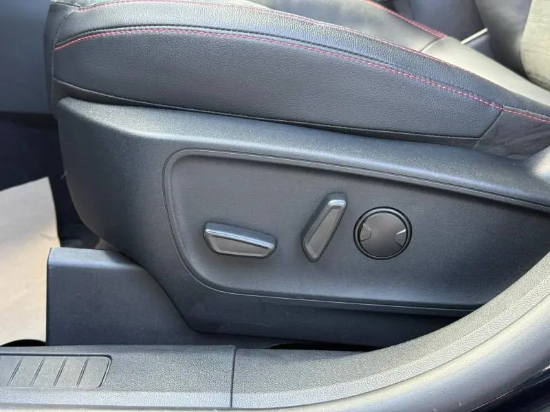 Gros plan sur les commandes électriques du siège conducteur noir avec surpiqûres rouges du Ford Kuga 2023 finition ST-Line X.