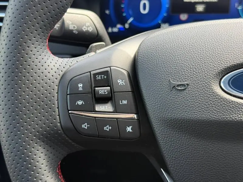 Gros plan sur les commandes de régulateur et volume au volant cuir noir perforé du Ford Kuga 2023 finition ST-Line X.