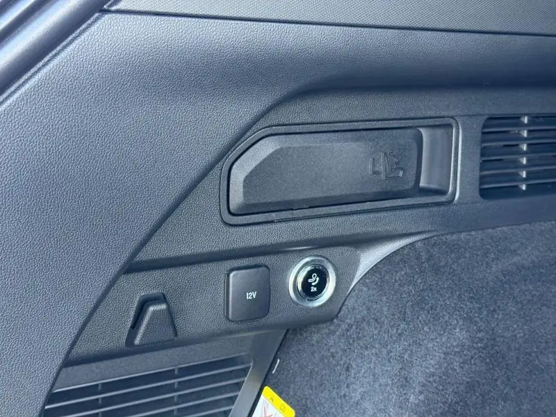 Détail intérieur du coffre noir avec prise 12V et commande électrique rabattement siège du Ford Kuga 2023 noir Agate.