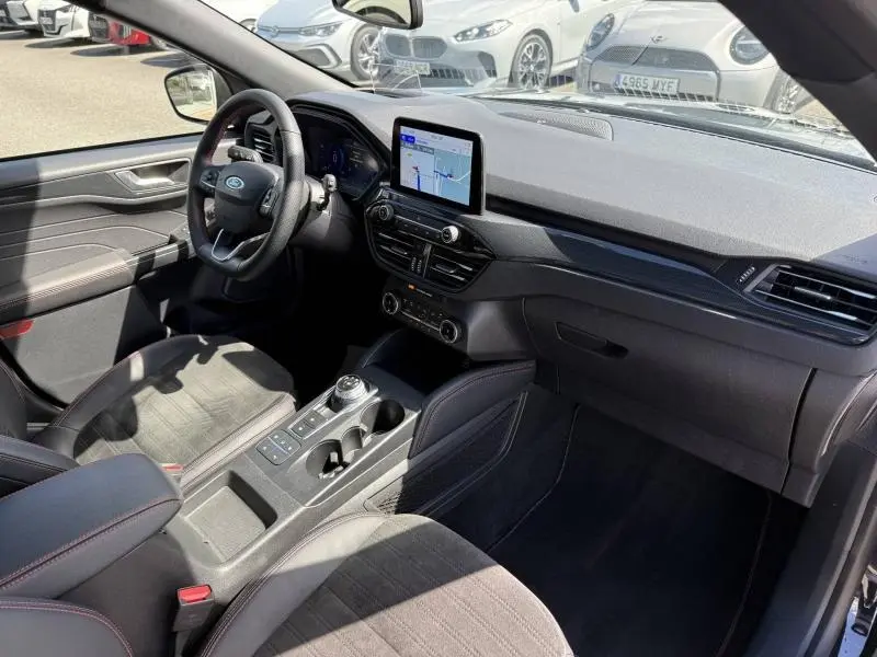 Vue intérieure côté conducteur du Ford Kuga 2023 noir Agate, avec écran tactile GPS et volant cuir multifonction.