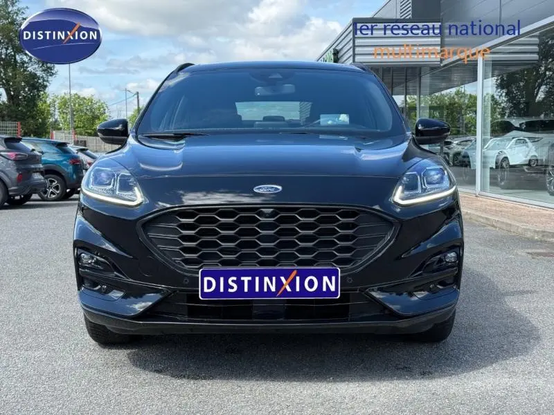 Vue avant d'un Ford Kuga 1.5 EcoBlue noir Agate métallisé avec calandre hexagonale et phares LED allumés.