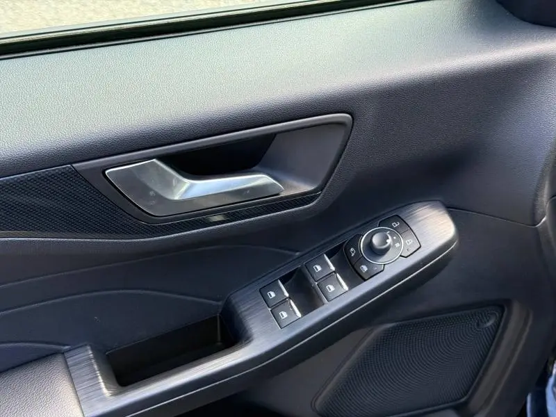 Détail de la porte avant gauche du Ford Kuga 2023 noir, avec commandes électriques des vitres et rétroviseurs.