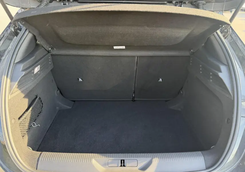 Coffre ouvert vu de l'arrière d'une Peugeot 308 noir Perla, montrant un espace de rangement vide et propre.