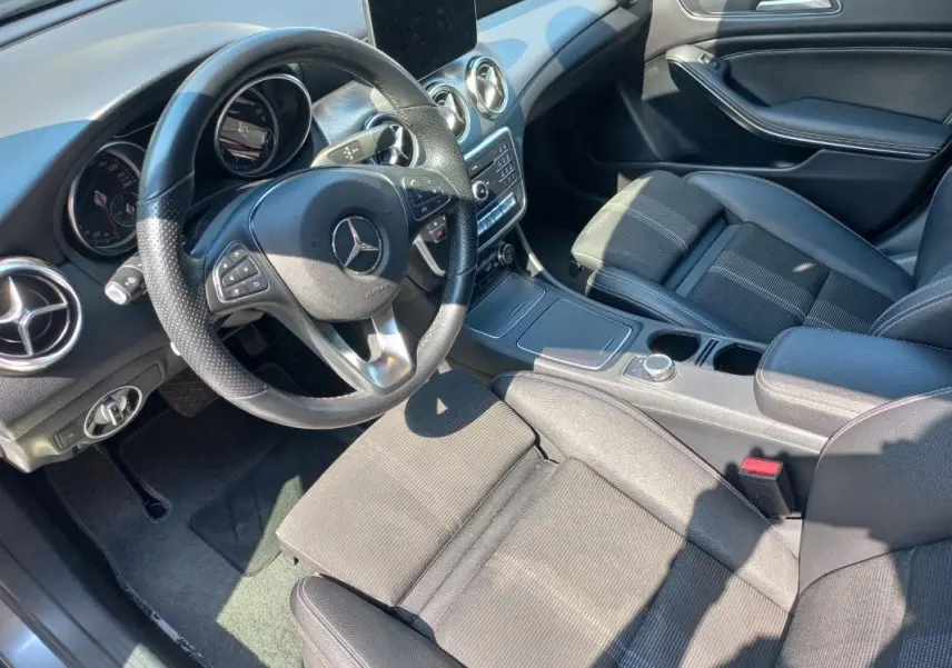 Intérieur de la Mercedes GLA 2019 vue côté conducteur, volant multifonction et sièges tissu gris en lumière naturelle.