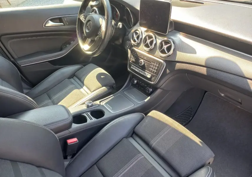 Vue intérieure côté conducteur du Mercedes GLA 2019 gris, avec tableau de bord moderne et sièges en tissu noir.