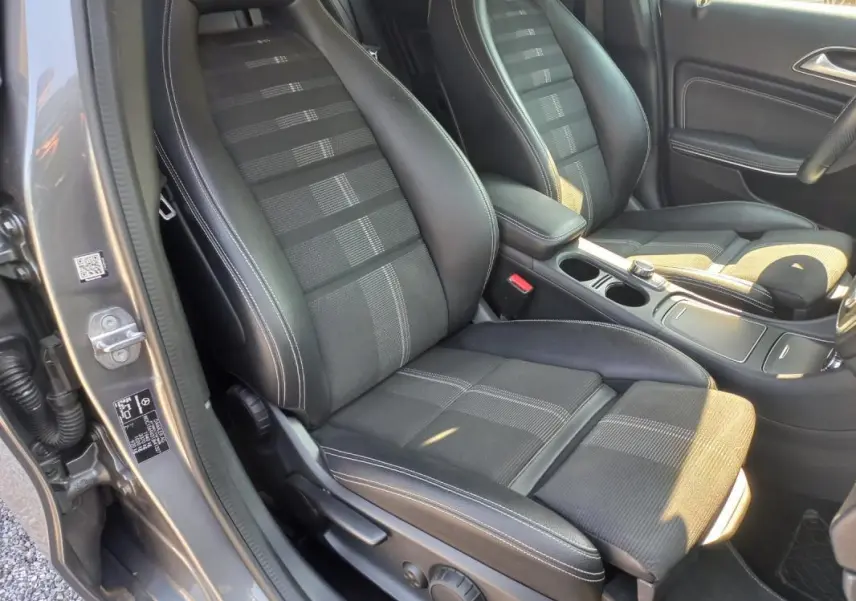 Vue intérieure côté conducteur du Mercedes GLA gris 2019, mettant en valeur les sièges en tissu et cuir avec surpiqûres blanches.