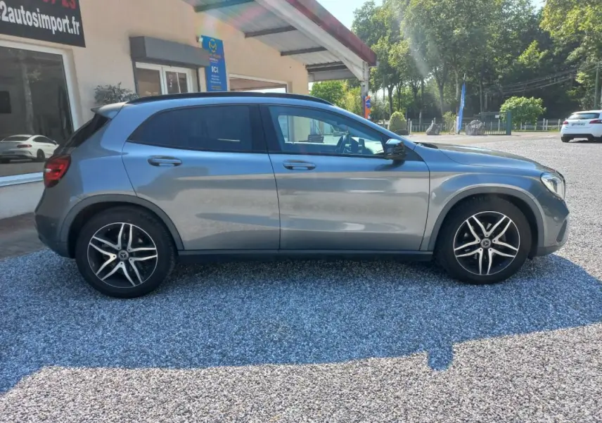 Vue de profil côté gauche d'un Mercedes GLA gris 2019 avec jantes alliage et vitres teintées, stationné sur gravier.