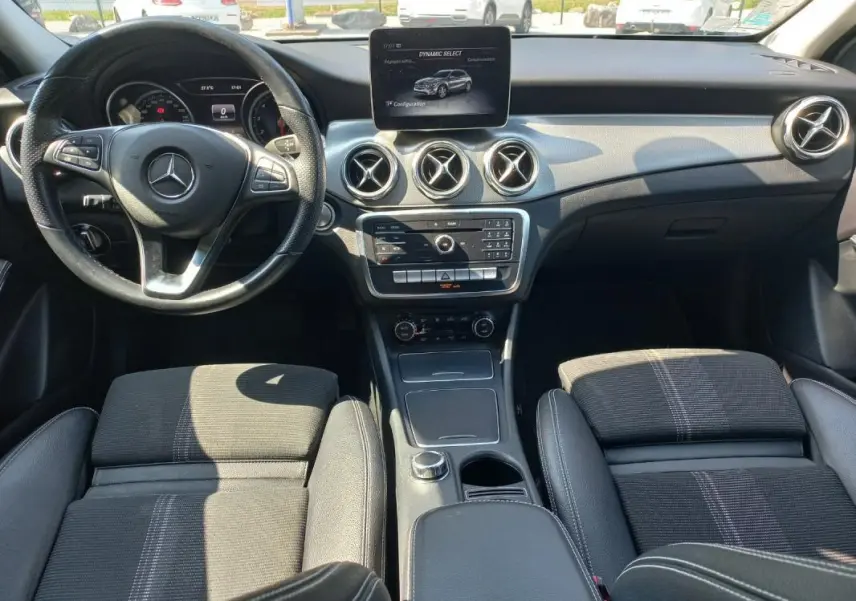 Vue intérieure avant du Mercedes GLA 2019 gris, montrant le tableau de bord, volant multifonction et écran central.
