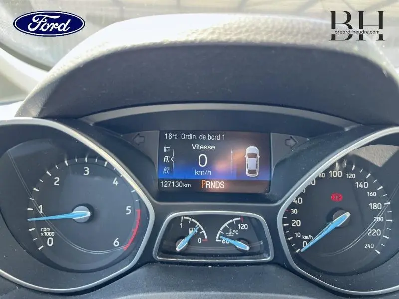 Vue rapprochée du tableau de bord numérique du Ford Grand C-MAX blanc, affichant vitesse à 0 km/h et compte-tours.