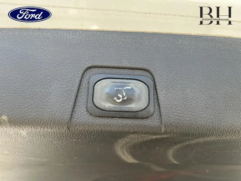 Bouton d'ouverture électrique du hayon sur le coffre d'un Ford Grand C-MAX blanc Glacier, vue rapprochée.