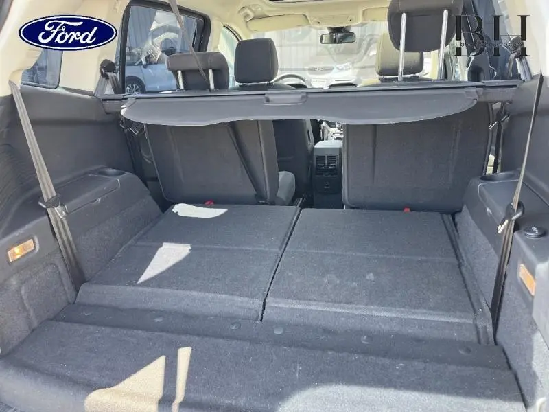 Vue arrière intérieure du coffre du Ford Grand C-MAX blanc avec sièges arrière rabattus et tablette cache-bagages déployée.