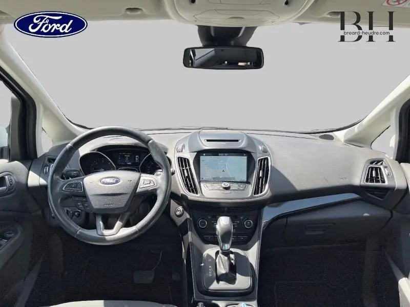 Vue intérieure avant du Ford Grand C-MAX blanc Glacier 2017, tableau de bord avec écran tactile et volant multifonction.