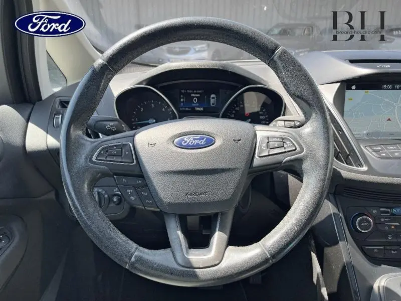 Vue centrée sur le volant en cuir noir d'une Ford Grand C-MAX 2017 avec tableau de bord et écran GPS visible.
