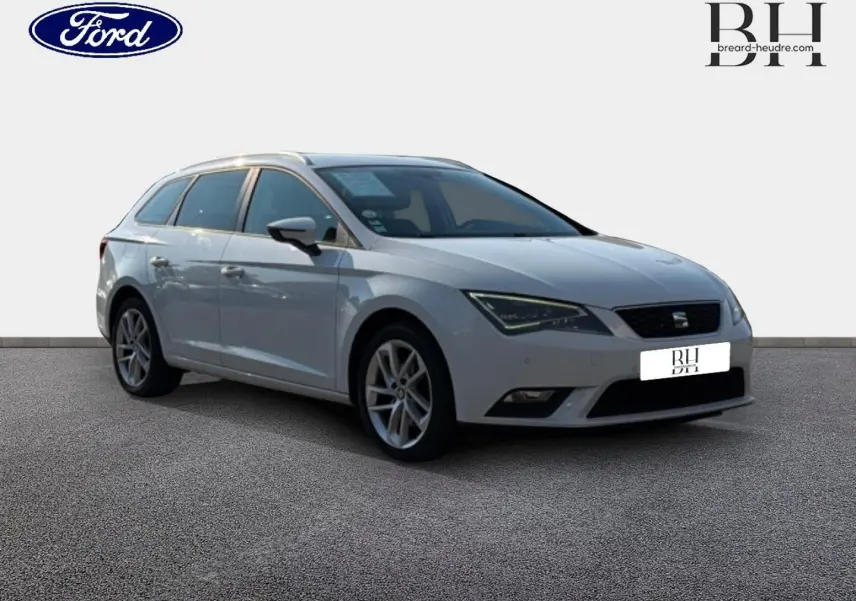 SEAT Leon ST blanc Candy vue 3/4 avant droit, avec jantes alu et barres de toit visibles.