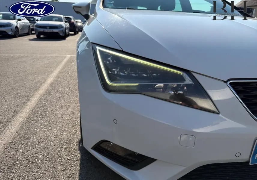 Gros plan sur le phare avant gauche d’une SEAT LEON ST blanc Candy, mettant en valeur son design LED anguleux.