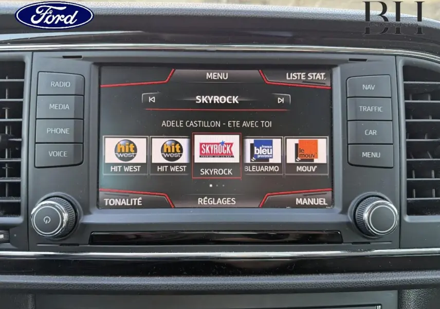 Écran tactile central de la console d'une SEAT LEON ST blanc Candy, affichant les stations radio avec commandes autour.
