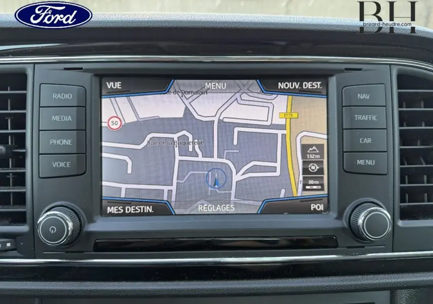 Vue de face sur l'écran tactile du système de navigation d'une SEAT LEON ST blanc Candy, affichant une carte GPS.