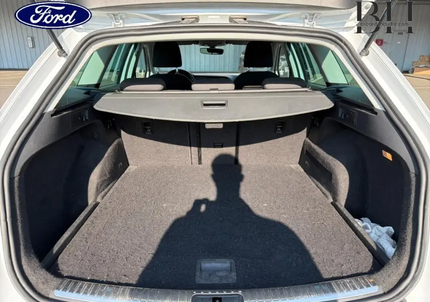 Coffre ouvert vu de l'arrière d'un SEAT LEON ST blanc Candy, montrant un espace de chargement vide avec cache-bagages.