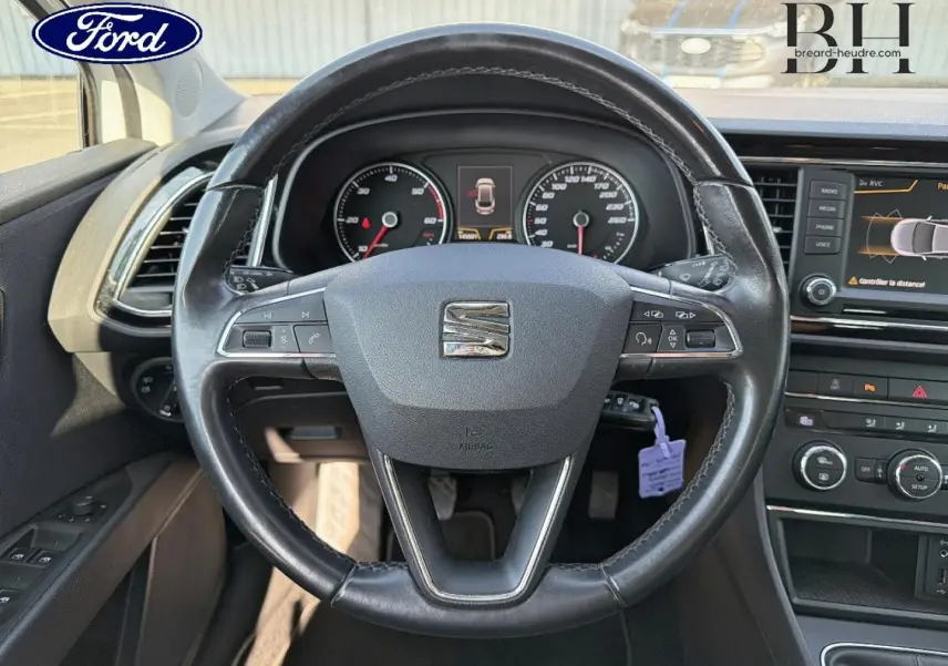 Volant cuir noir vu de face dans l'habitacle d'une SEAT LEON ST, avec tableau de bord et écran tactile visible.