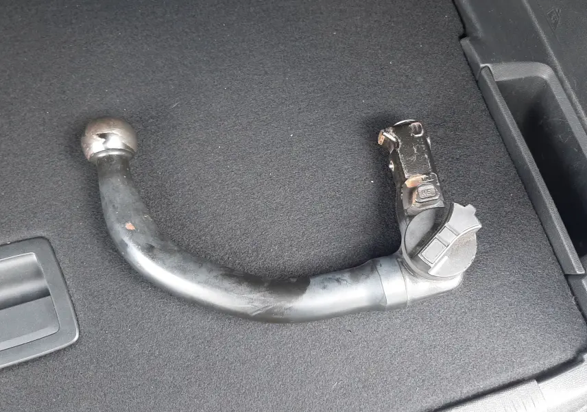 Gros plan sur une barre d'attelage noire posée dans le coffre d'un Peugeot 3008 blanc nacré avec toit noir.