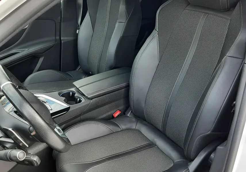 Vue intérieure rapprochée des sièges avant en cuir noir du Peugeot 3008 2022, avec console centrale et volant partiel visible.